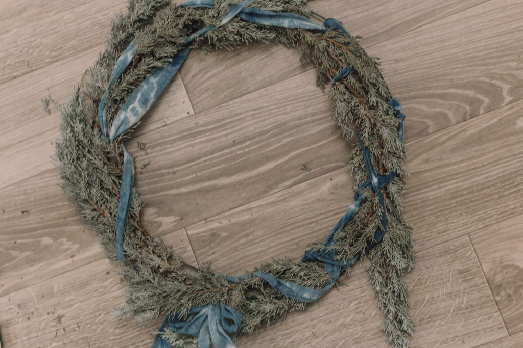 This indigo shibori wreath DIY wreath is a simple touch of greenery and holidays to your door with a pop of color that is very on trend.
