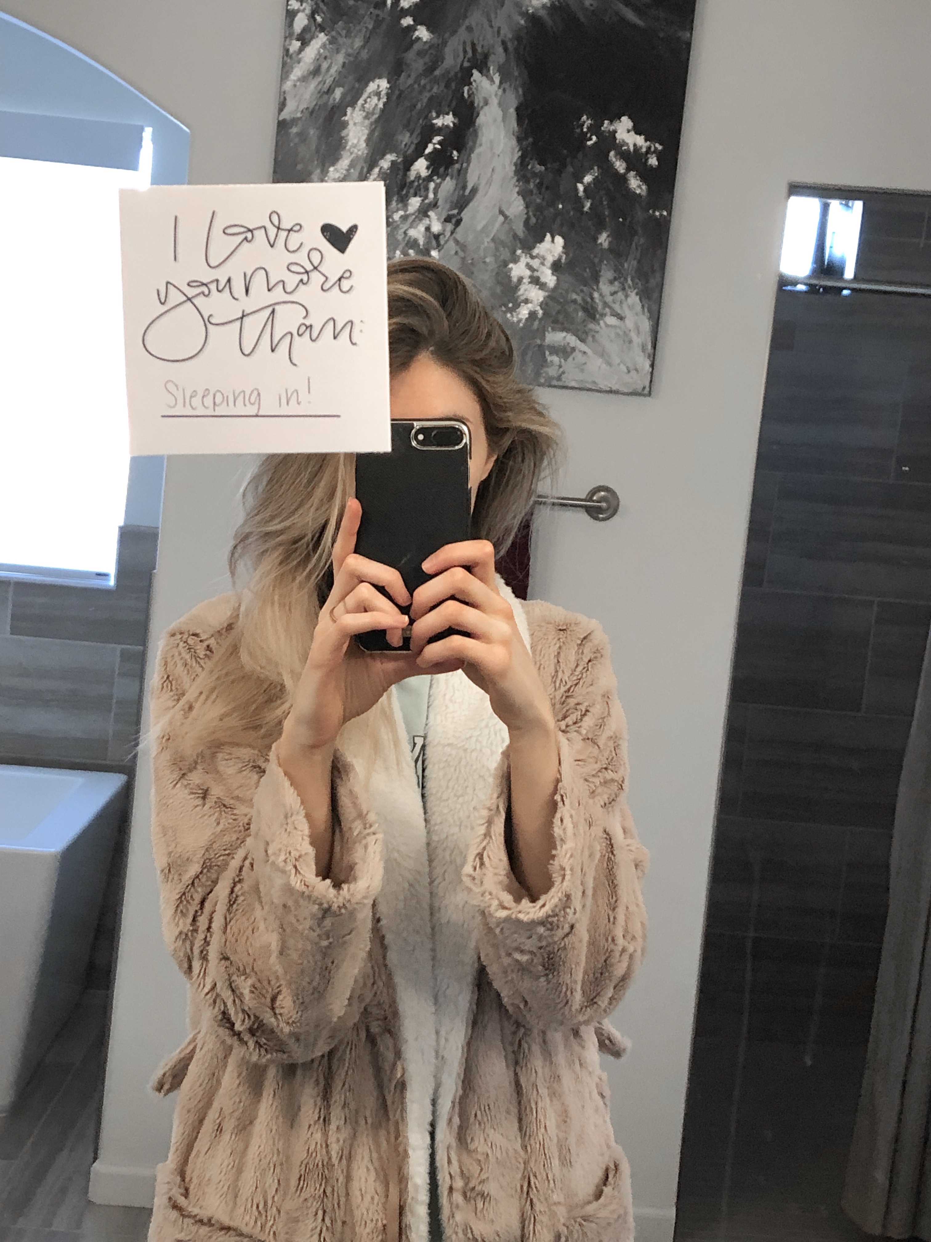 Girl standing in front of bathroom mirror taking a picture of a love note on the mirror
